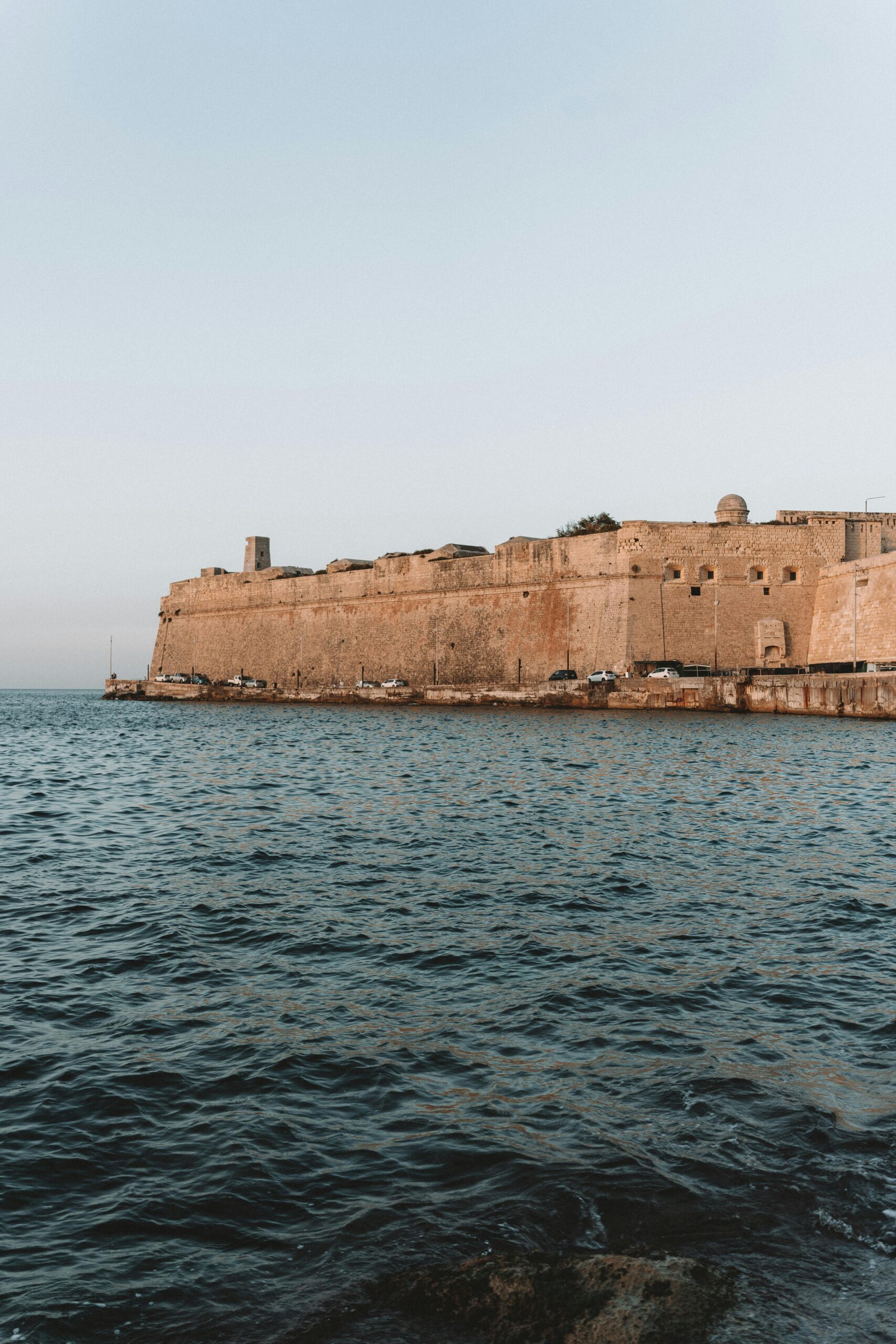 Scenic view of Fort St. Angelo in Malta with calm waters at sunset.