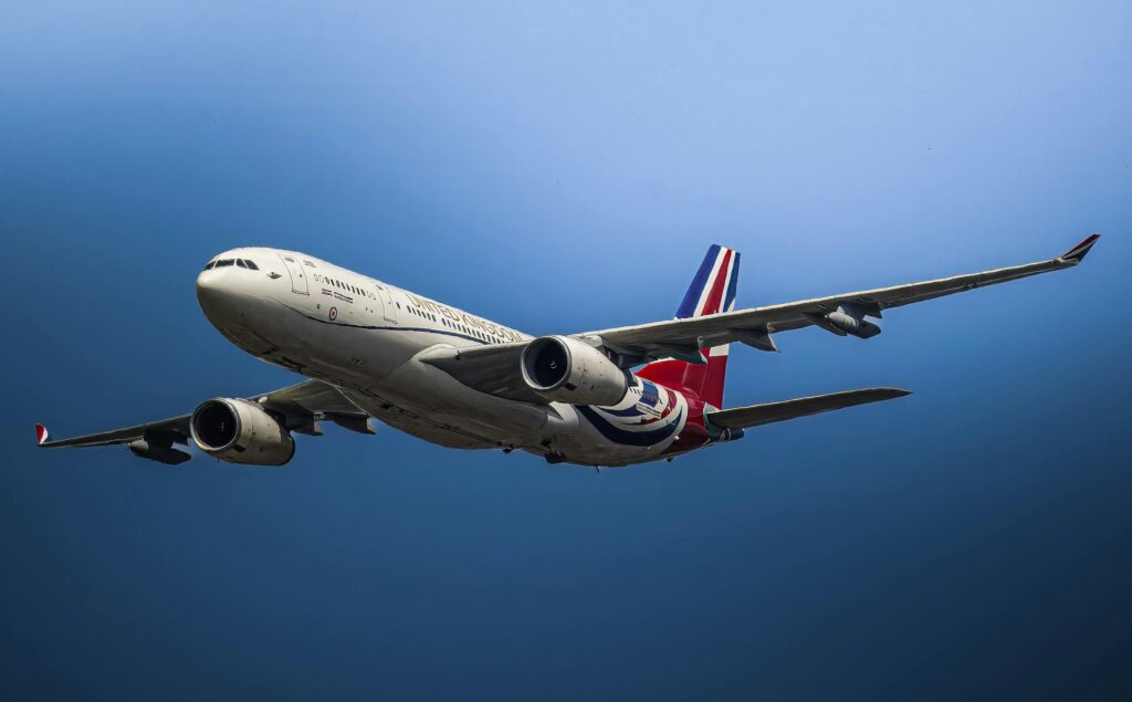 A close-up view of a commercial airplane flying against a clear blue sky.